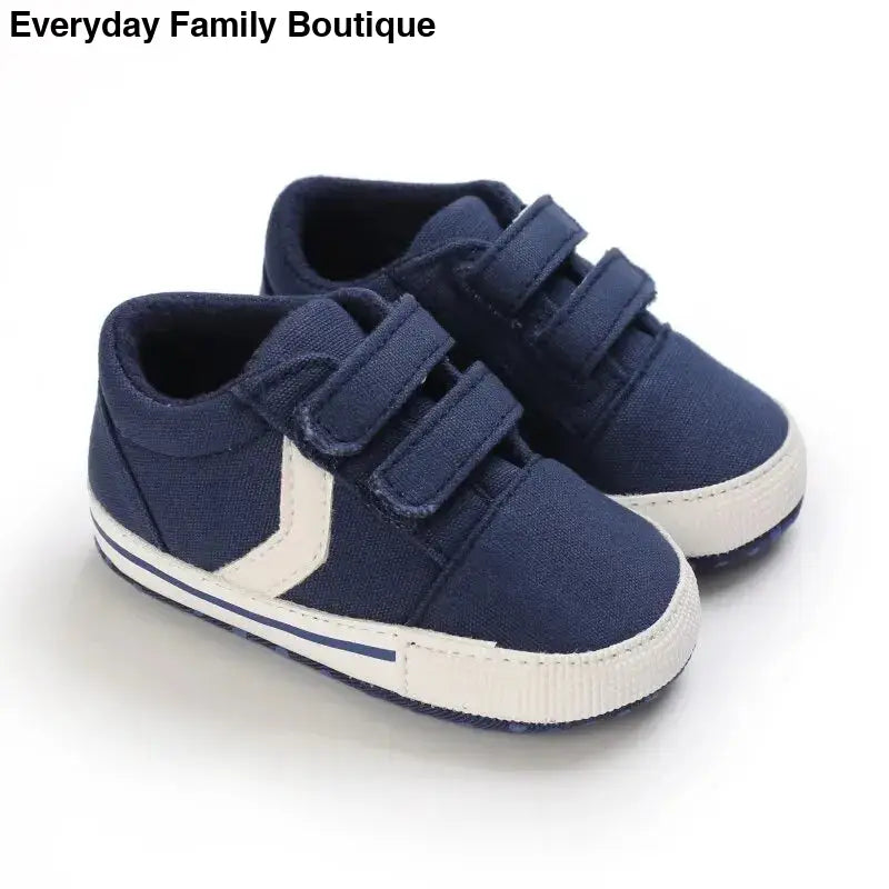 Navy blue baby sneakers with white stripes and velcro straps.