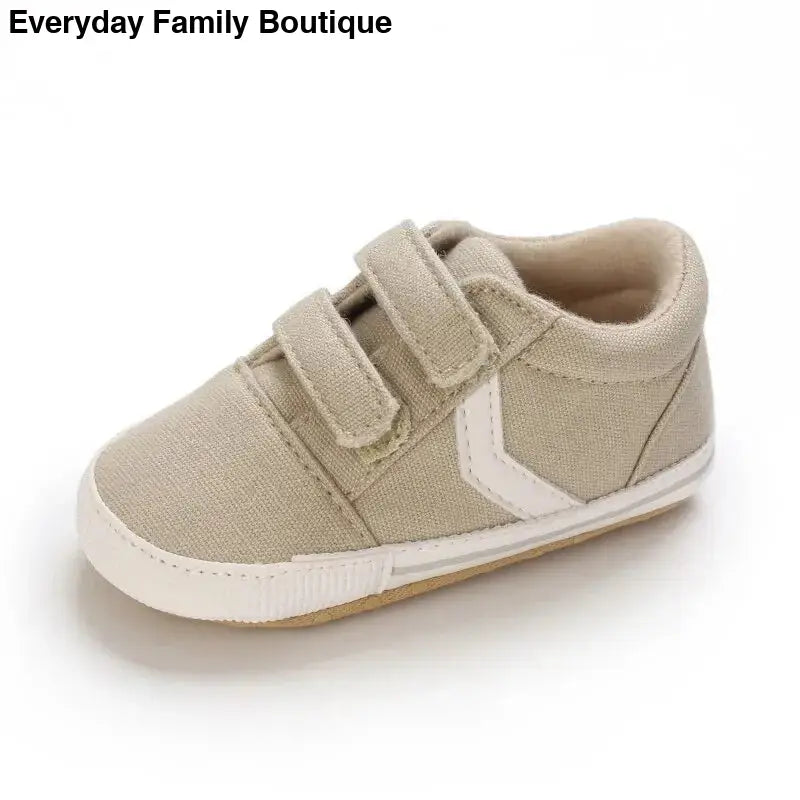 Beige canvas baby shoe with velcro straps and white side detail.