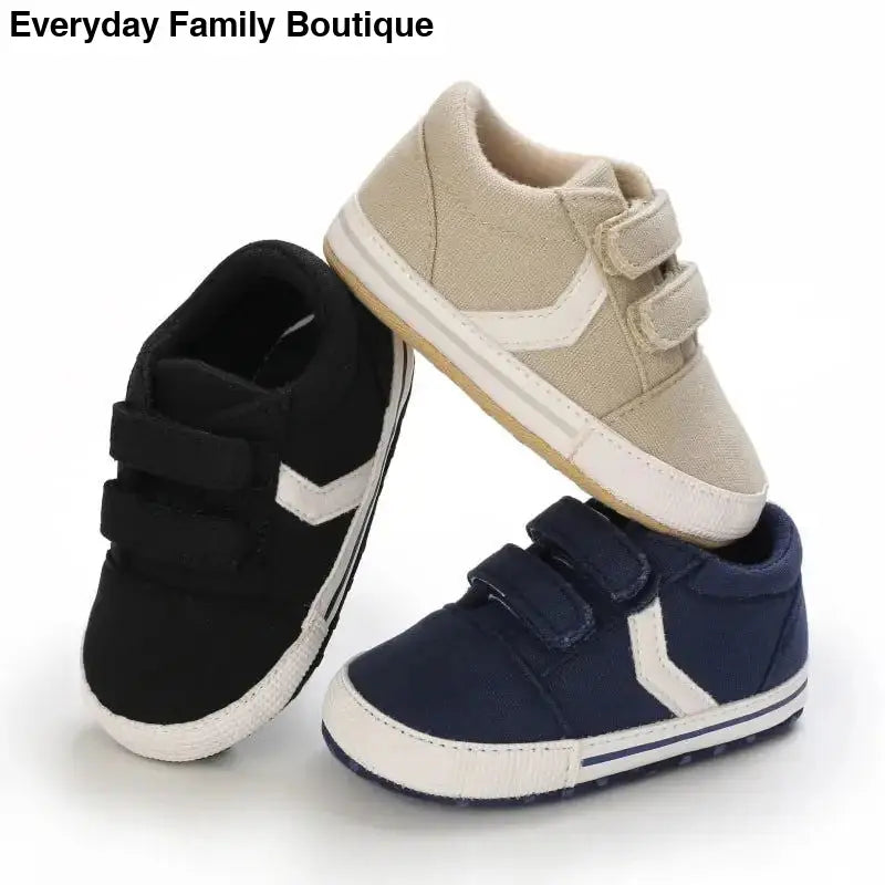 Three baby sneakers in beige, black, and navy blue colors with velcro straps.