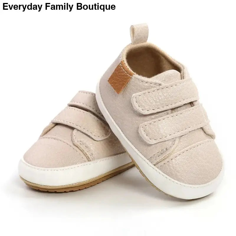 Beige baby sneakers with velcro straps and white soles.