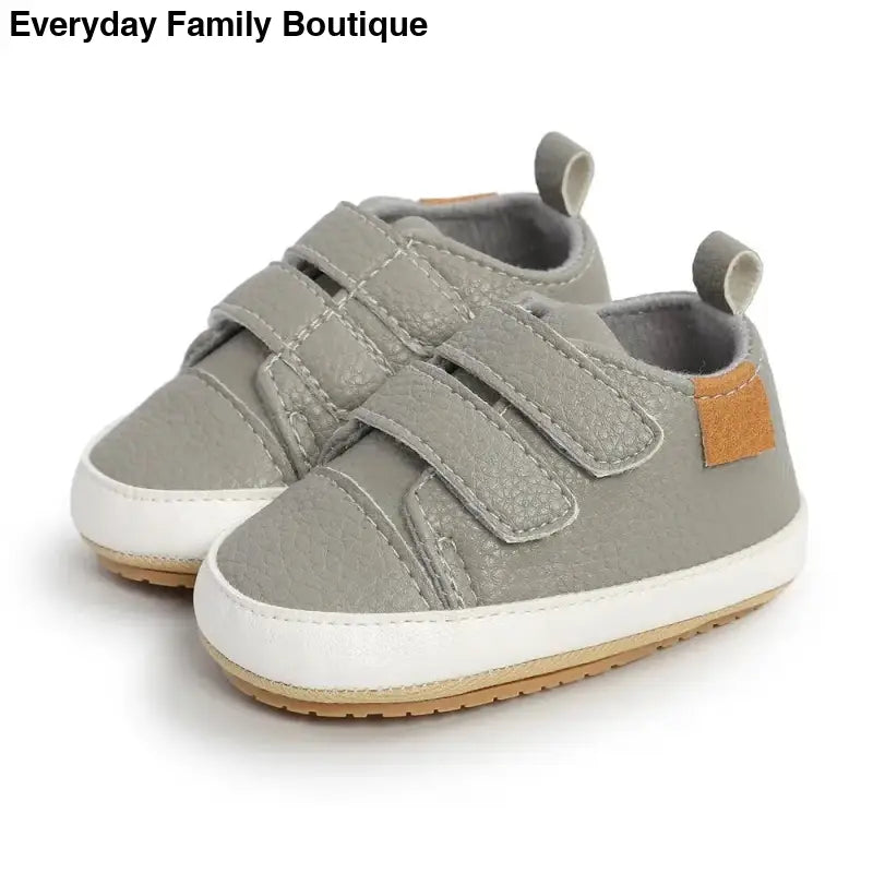 Gray canvas baby shoes with velcro straps and white soles.