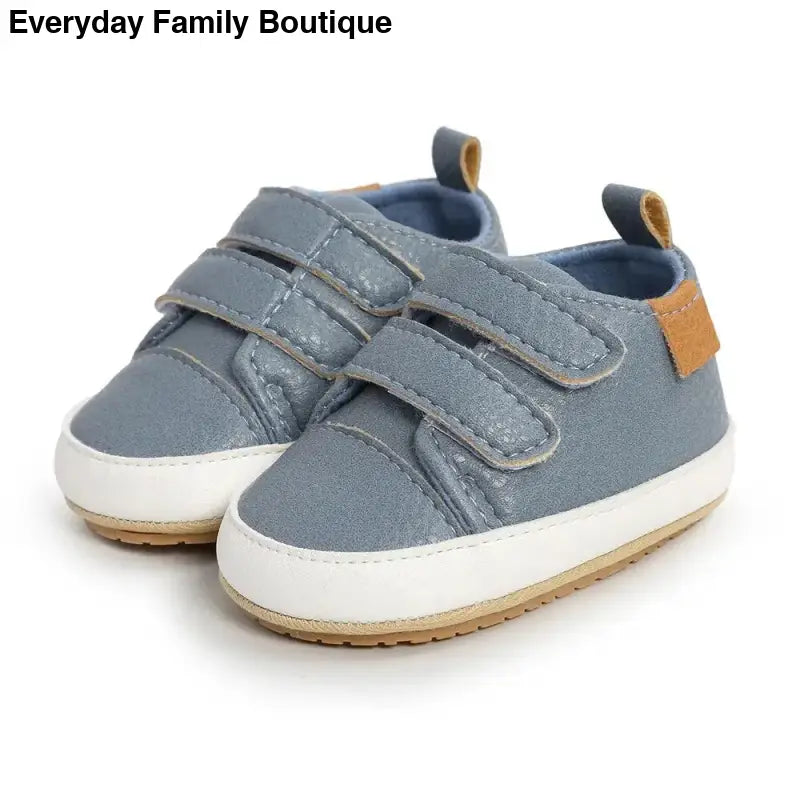 Gray baby shoes with velcro straps and white soles.