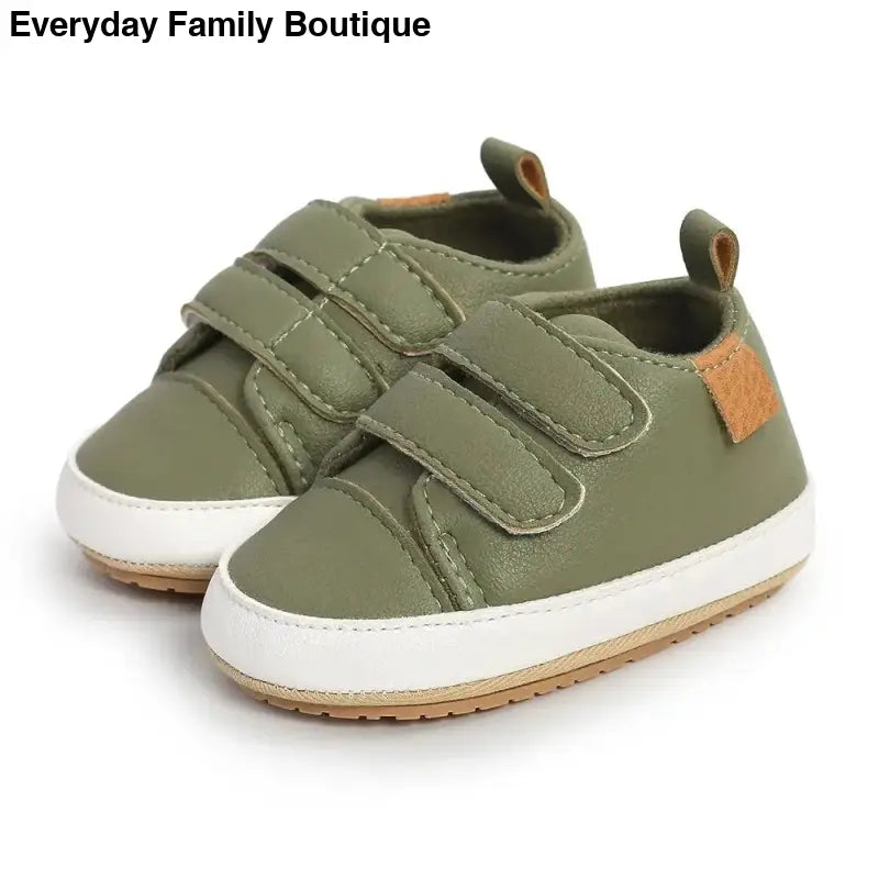 Olive green baby sneakers with velcro straps and white soles.