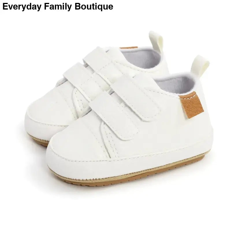 White velcro baby sneakers with a tan accent patch.