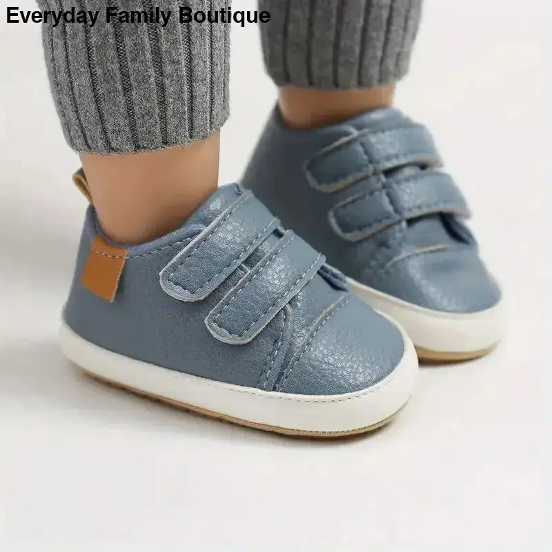 Blue velcro baby sneakers with a tan leather accent.