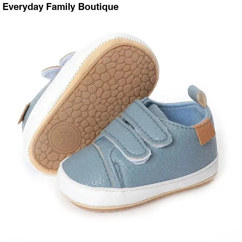 Light blue baby sneaker with velcro straps and a tan rubber sole.