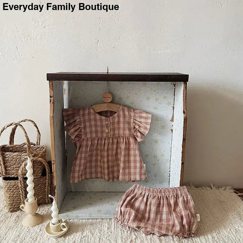 Pink and brown plaid baby outfit with ruffled sleeves and matching bloomers.