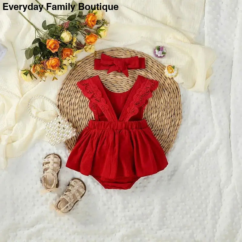 Red lace-trimmed baby romper with ruffled shoulder straps.