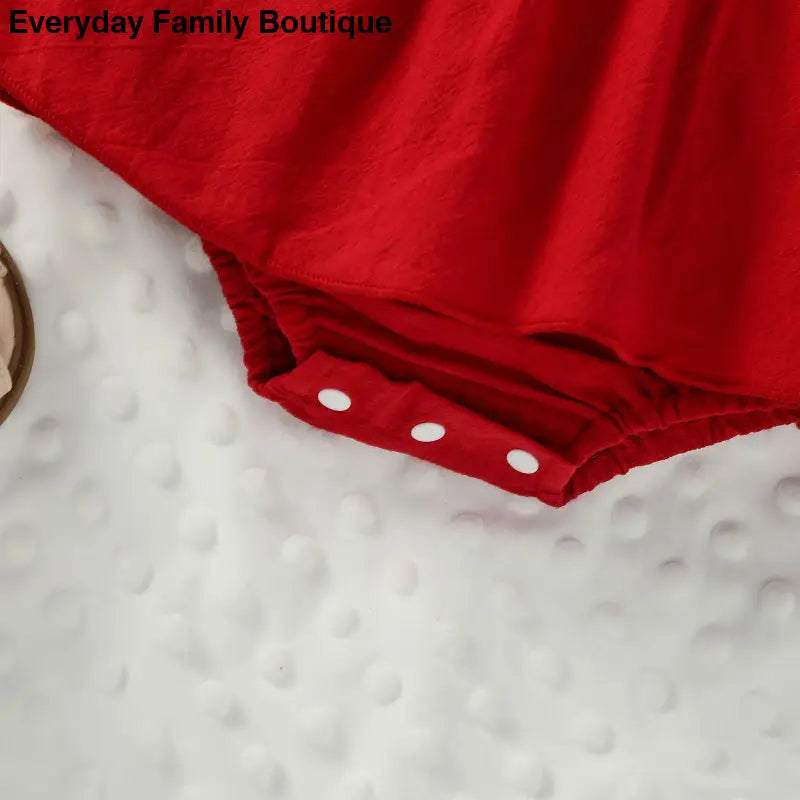 Red dress with white polka dot buttons against white textured fabric.