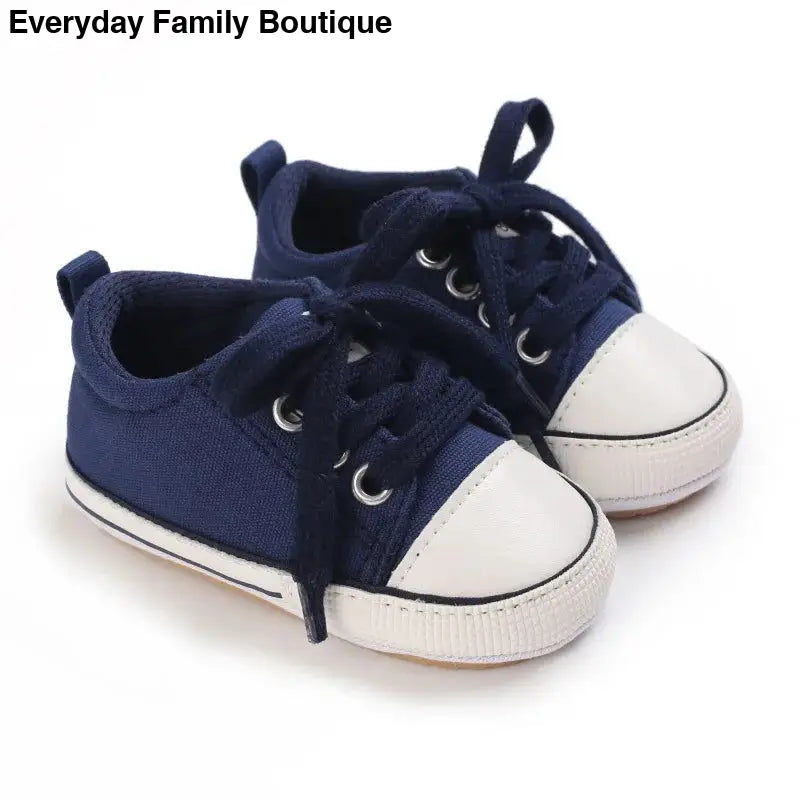 Navy blue canvas baby sneakers with white rubber toe caps and laces.