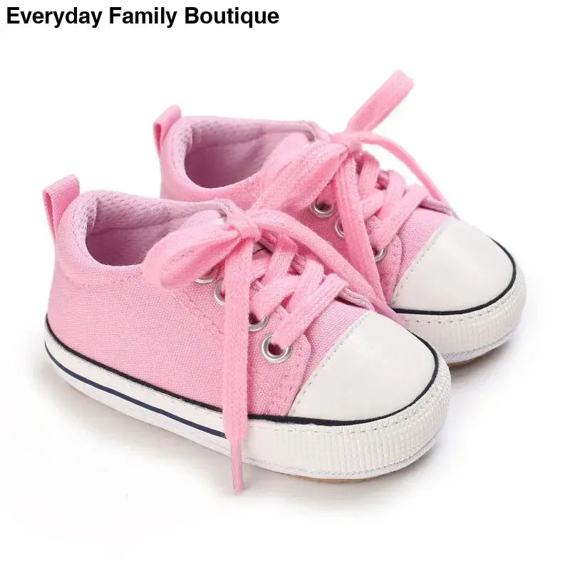 Pink canvas sneakers with white rubber toes and laces.