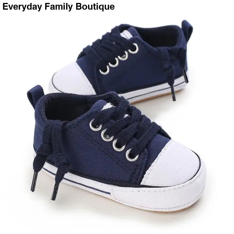 Navy blue canvas baby sneakers with white toe caps and laces.