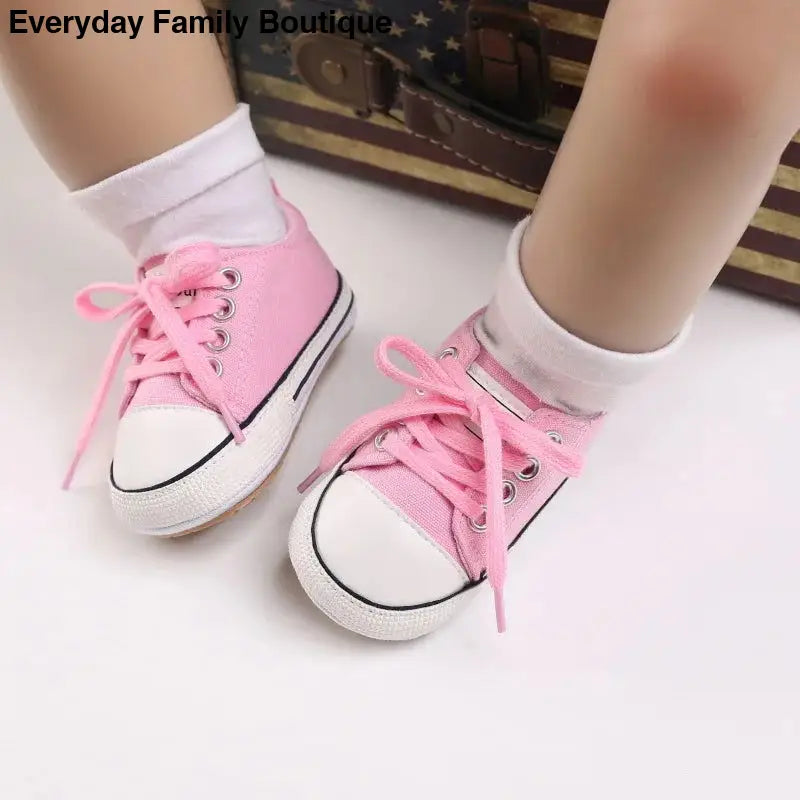 Pink canvas sneakers with white toe caps and laces.