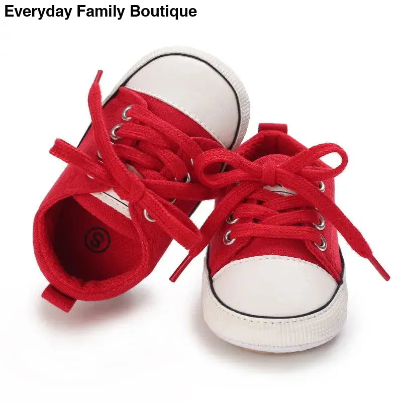 Red and white canvas baby sneakers with laces.