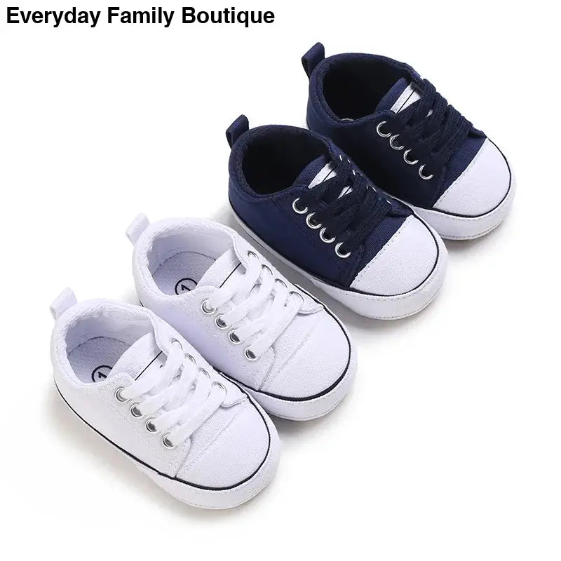 Two pairs of baby sneakers in navy blue and white colors.