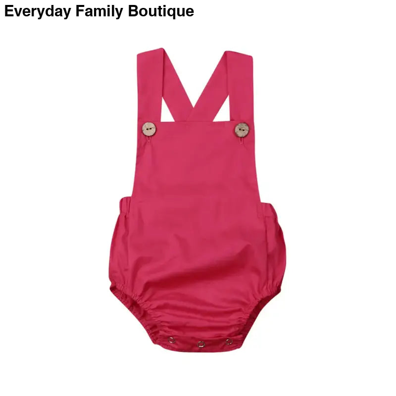 Pink baby romper with shoulder straps and snap closures.