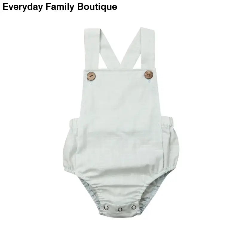 White cotton baby romper with cross-back straps and button closures.