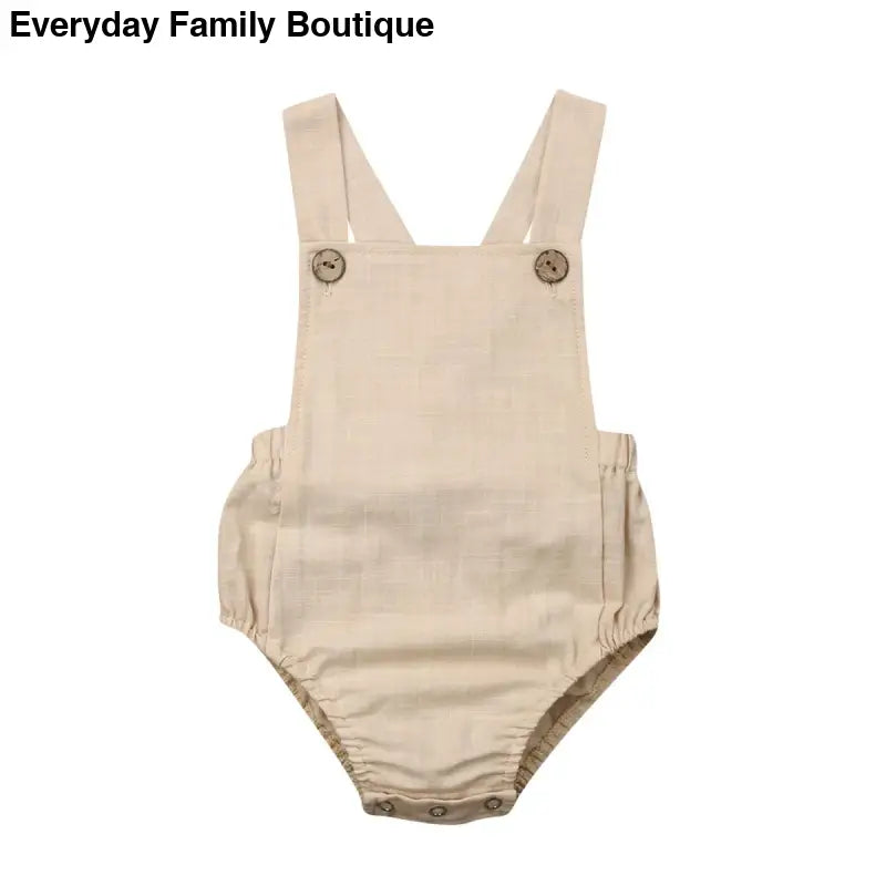 Beige cotton baby romper with shoulder straps and button closures.