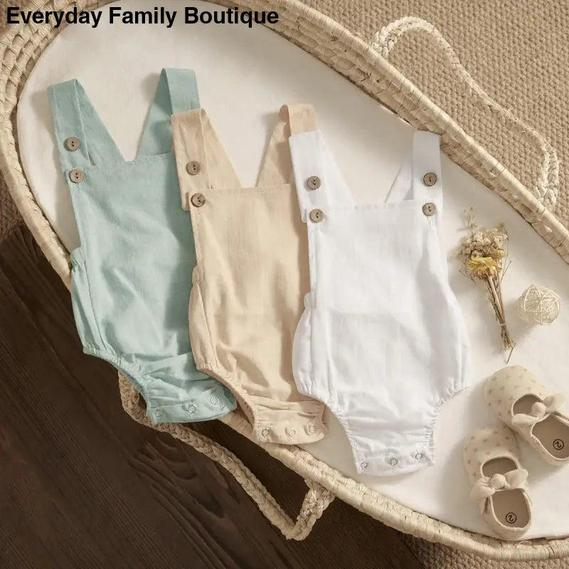 Three baby rompers in mint green, beige, and white colors with button straps.