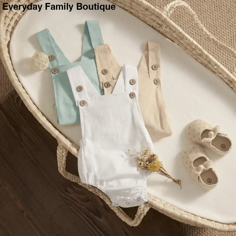 Baby overalls in white, mint, and beige colors with button details.