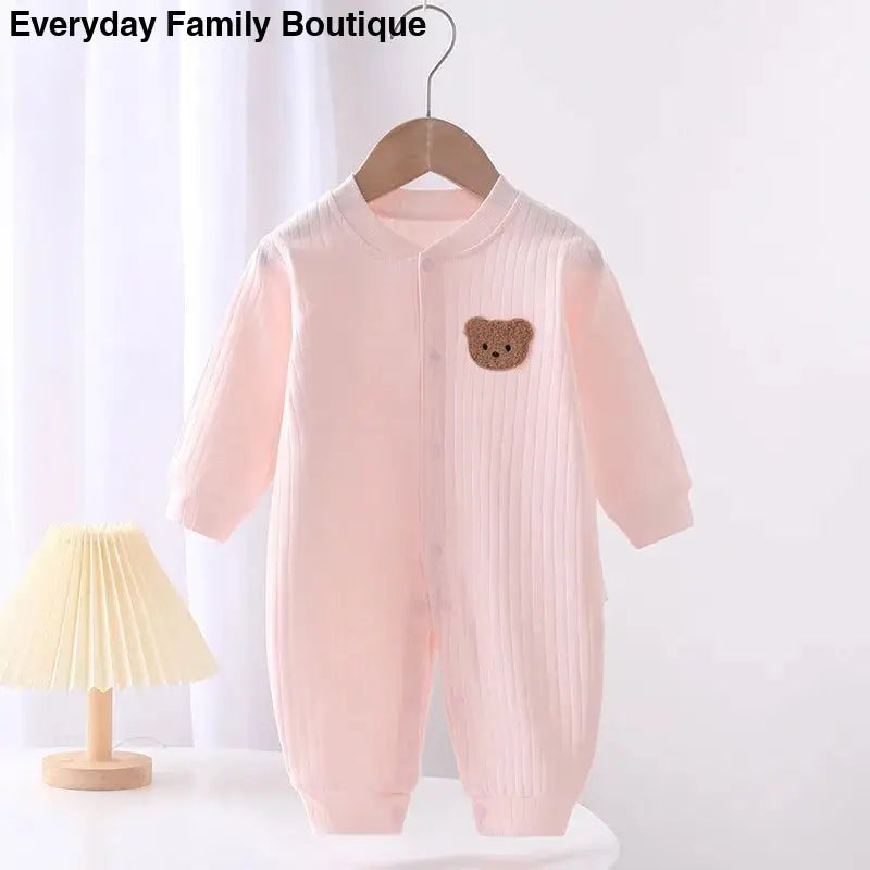 Pink baby onesie with a brown teddy bear patch.