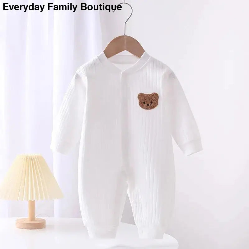 White baby romper with a brown teddy bear patch.