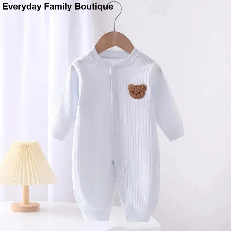 White knit baby romper with a brown teddy bear patch.