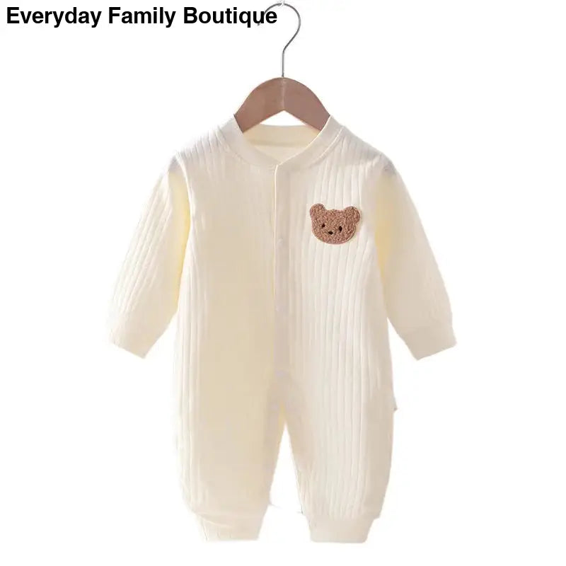 Cream-colored ribbed baby romper with a brown teddy bear patch.