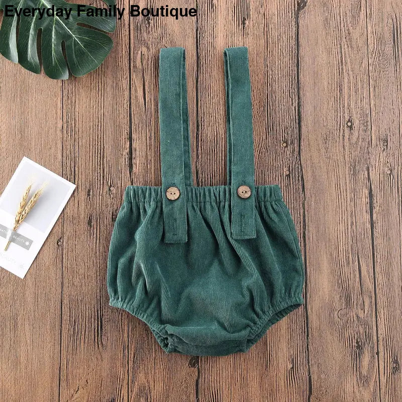 Green corduroy baby romper with suspender straps and buttons.