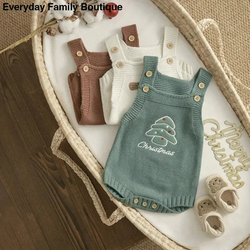 Knitted baby romper in sage green with an embroidered Christmas tree design and button straps.