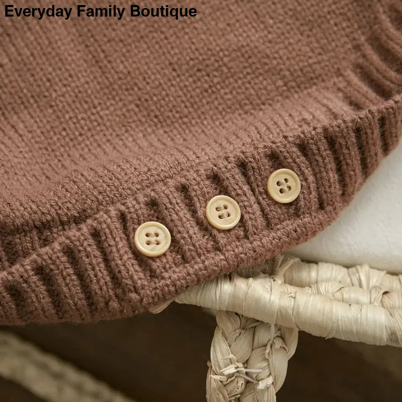 Brown knitted fabric with decorative beige buttons along the edge.