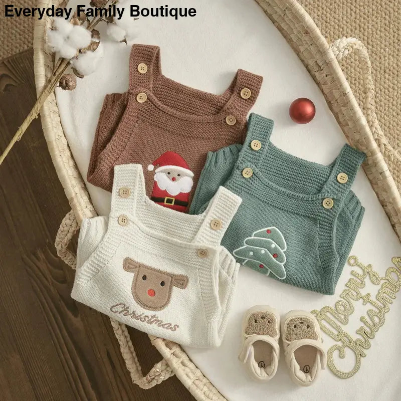 Three knitted baby overalls with Christmas-themed designs and a pair of tiny shoes.