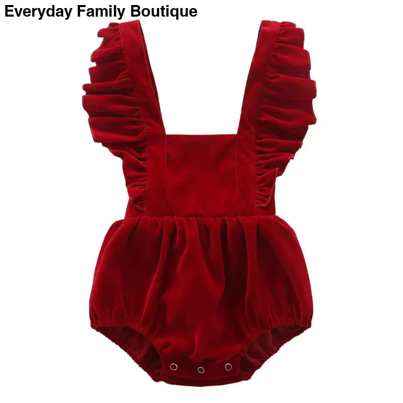 Red velvet baby romper with ruffled shoulder straps.