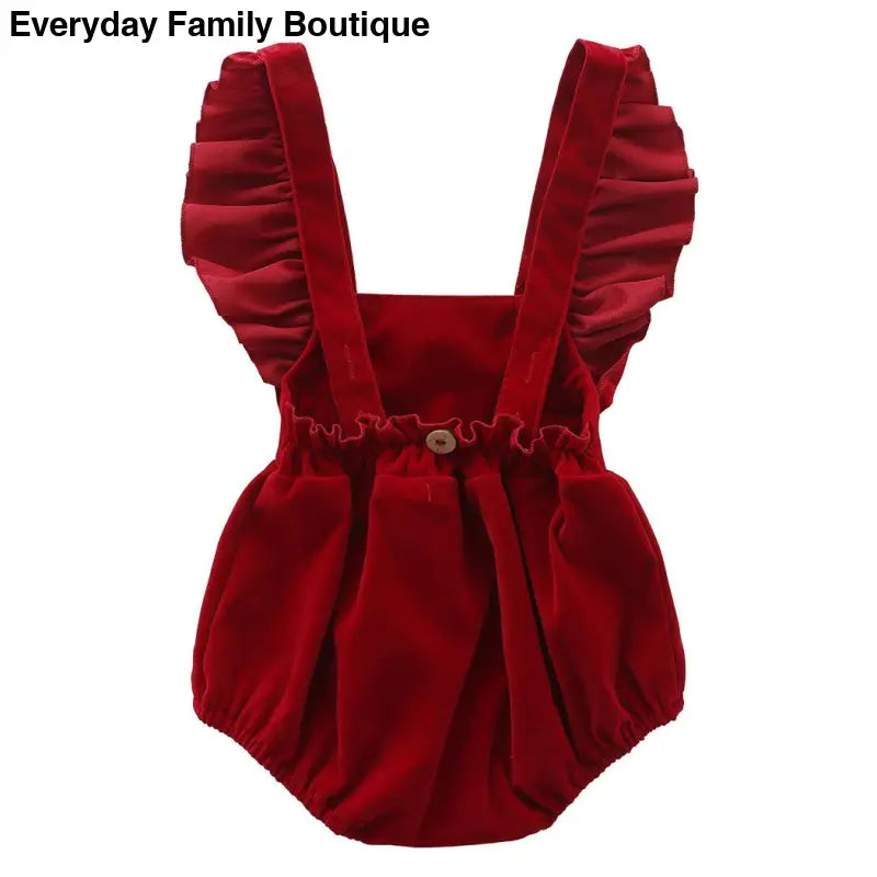 Red velvet baby romper with ruffled straps.