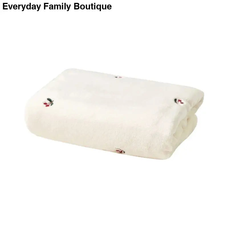 White folded blanket or duvet with small red floral embroidery.