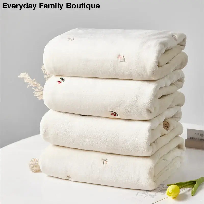 Stack of folded white cotton towels with small embroidered details and tassels.