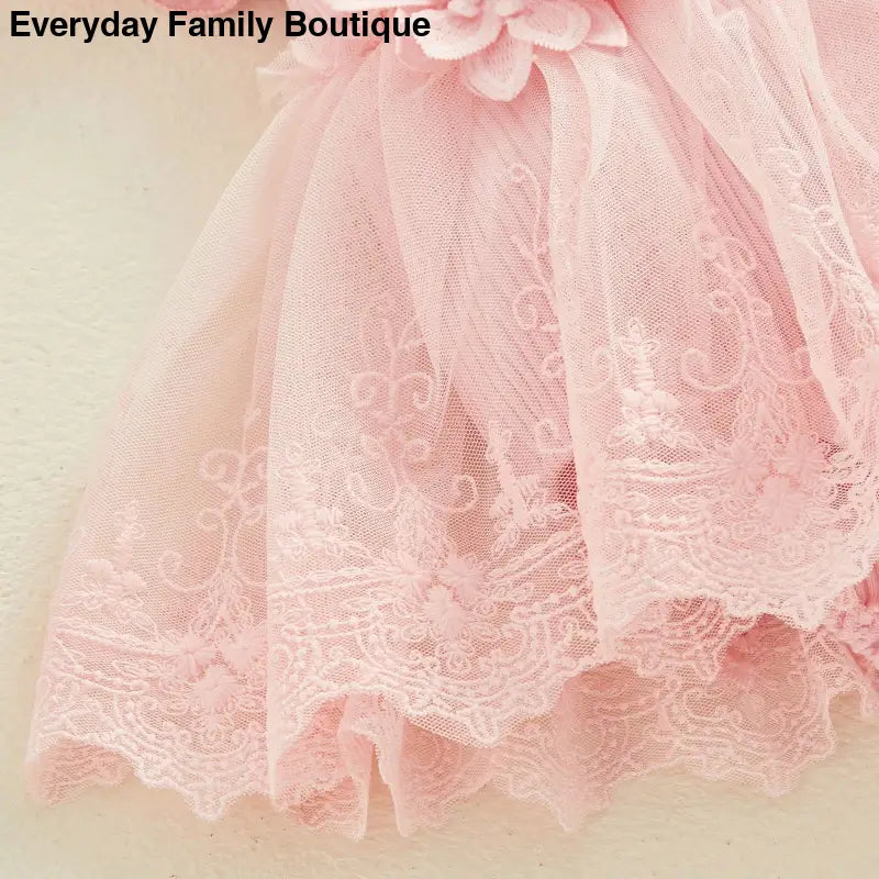 Delicate pink lace tulle fabric with floral embroidered details.