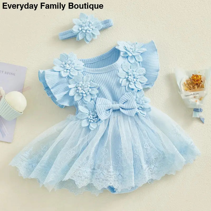 Light blue tulle dress with floral appliques and ruffled sleeves.