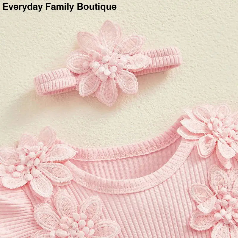 Pink ribbed fabric garment decorated with delicate floral appliques.