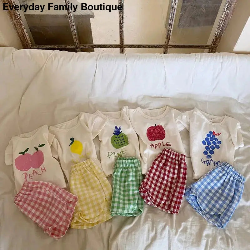 Five matching sets of children’s t-shirts and gingham shorts with fruit designs.