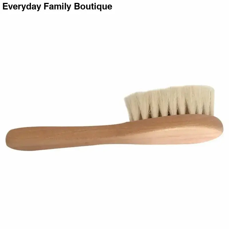 Wooden brush with soft white bristles and a long handle.