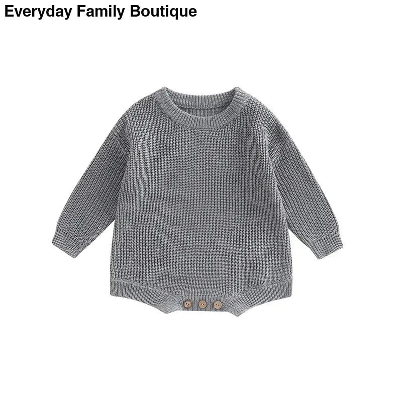 Gray knitted sweater with button details at the bottom hem.