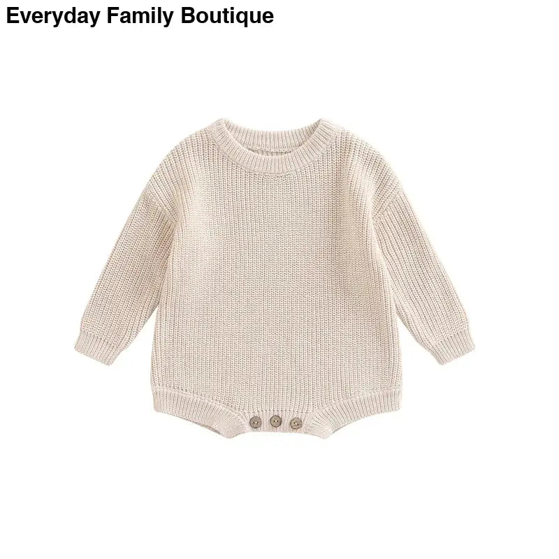 Cream-colored knitted baby romper with button details at the bottom.