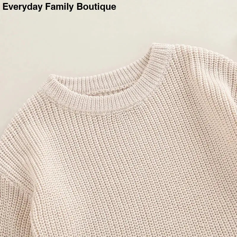 Cream-colored knit sweater with a ribbed crew neckline.