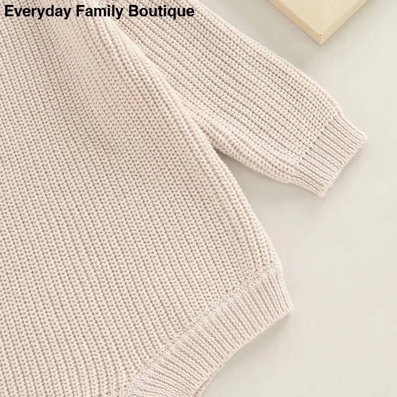 Cream-colored knit sweater with ribbed edges.