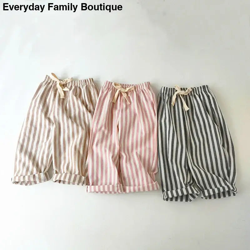 Three pairs of striped cotton shorts with drawstring waists in beige, pink, and gray colors.