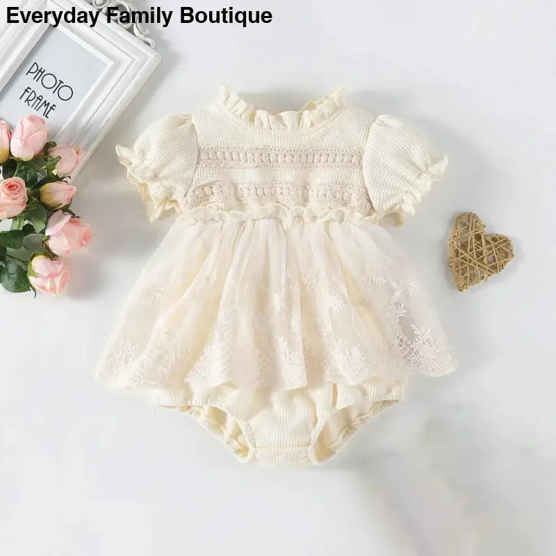 Cream-colored smocked baby romper dress with puff sleeves and matching bloomers.