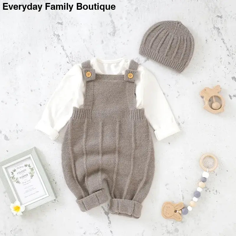 Knitted gray baby overalls with shoulder straps paired with a white long-sleeve shirt and matching beanie.