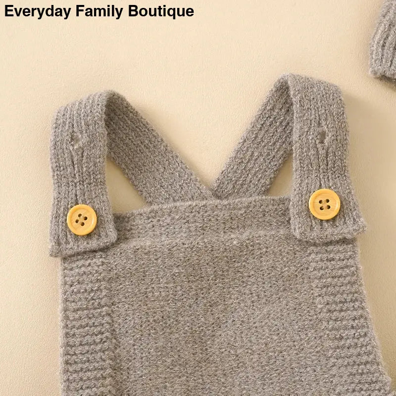 Gray knitted overalls with yellow buttons on the straps.