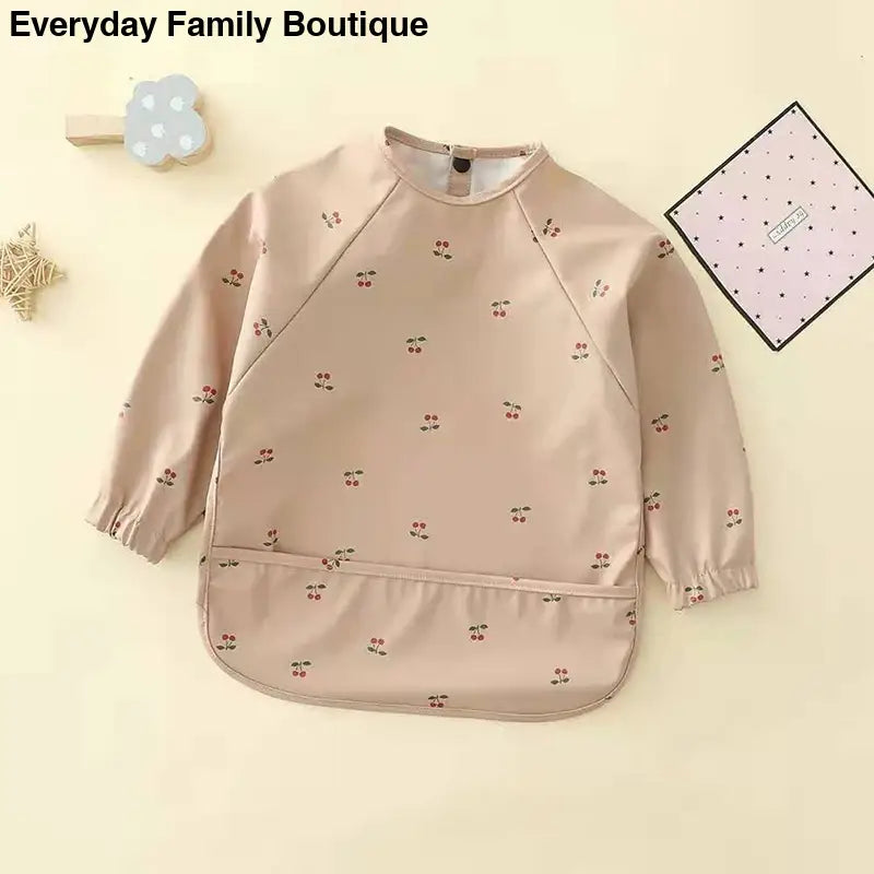 Beige long-sleeved smock with tiny floral print pattern.